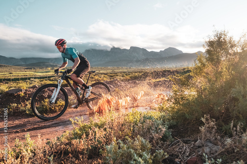 mountain biker riding through a muddy puddle