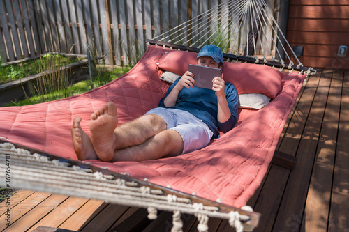 Young man in a hammock with a tablet