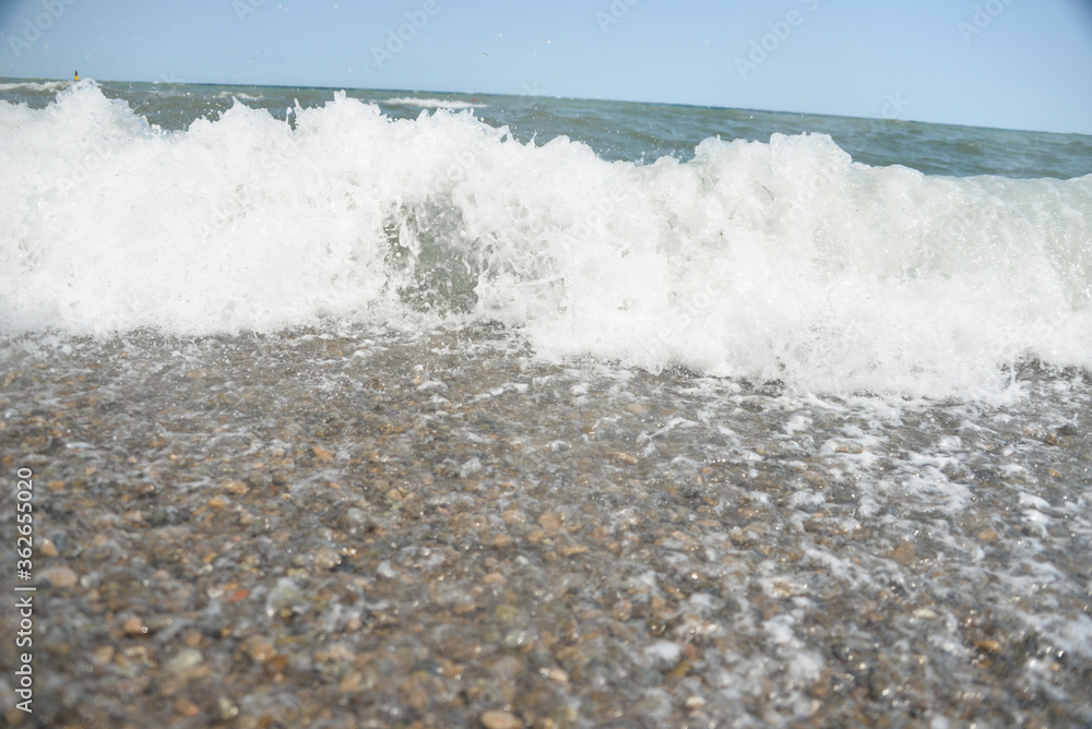 Fototapeta premium during the day the sea waves and splashes of small drops fall on the shore