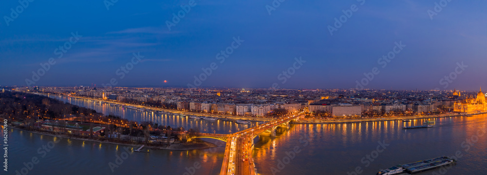 Panoramic Aerial drone shot of Margaret Bridge with lights on over Danube river during Budapest sunset