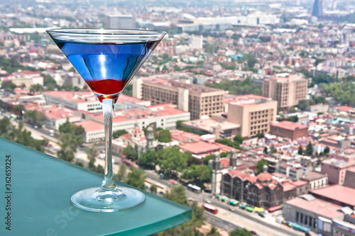 coctel Martini de curazao azul con cereza, de fondo vista panorámica de la ciudad	 photo