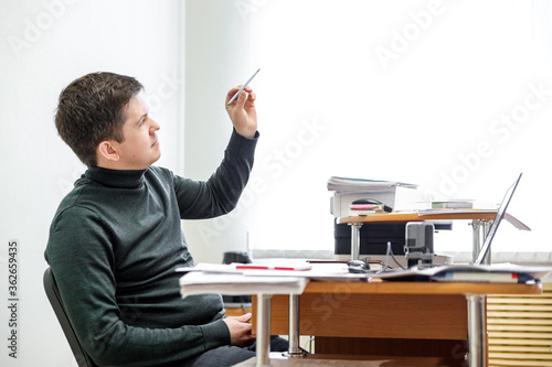 A casual businessman works in an office, sits at a Desk, types on a keyboard, looks at a computer screen. Concept of office work.