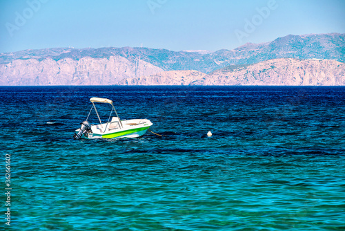 Small motor boat on a sea during summer day, mountains at the background