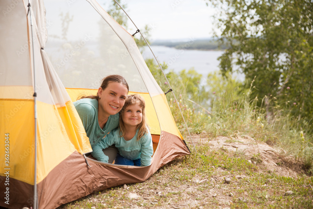 Happy family mom and child on camping trip relaxing inside tent. Staycations, hyper-local travel,  family outing, getaway.