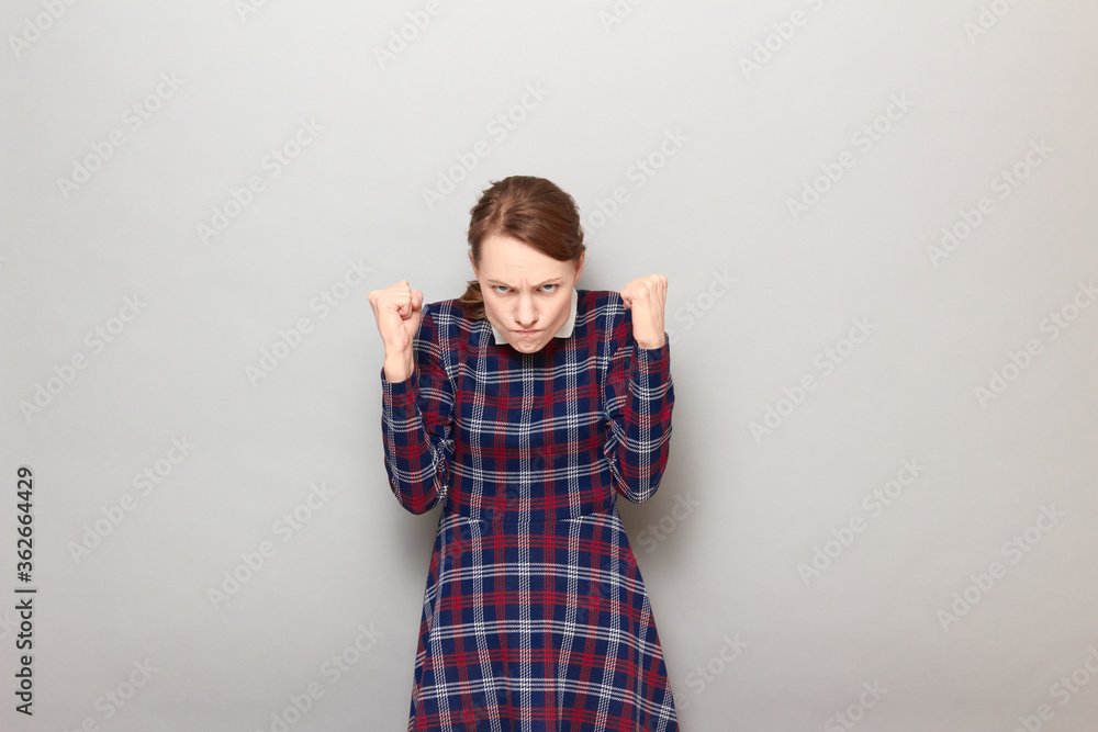 Portrait of angry furious young woman raising both fists up