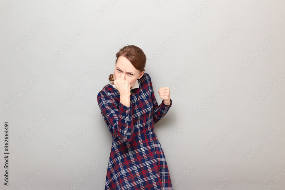 Portrait of angry young woman raising fist up in threatening gesture Portrait of angry young woman raising fist up in threatening gesture