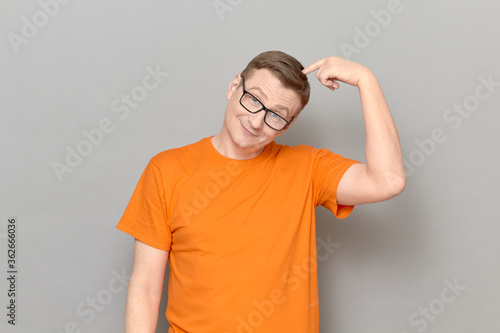 Portrait of happy mature man touching head with finger and thinking