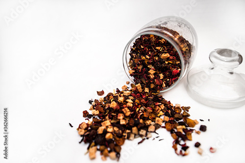 Dry tea in a glass jar on a white background. Leaves of red and black tea.Concept.