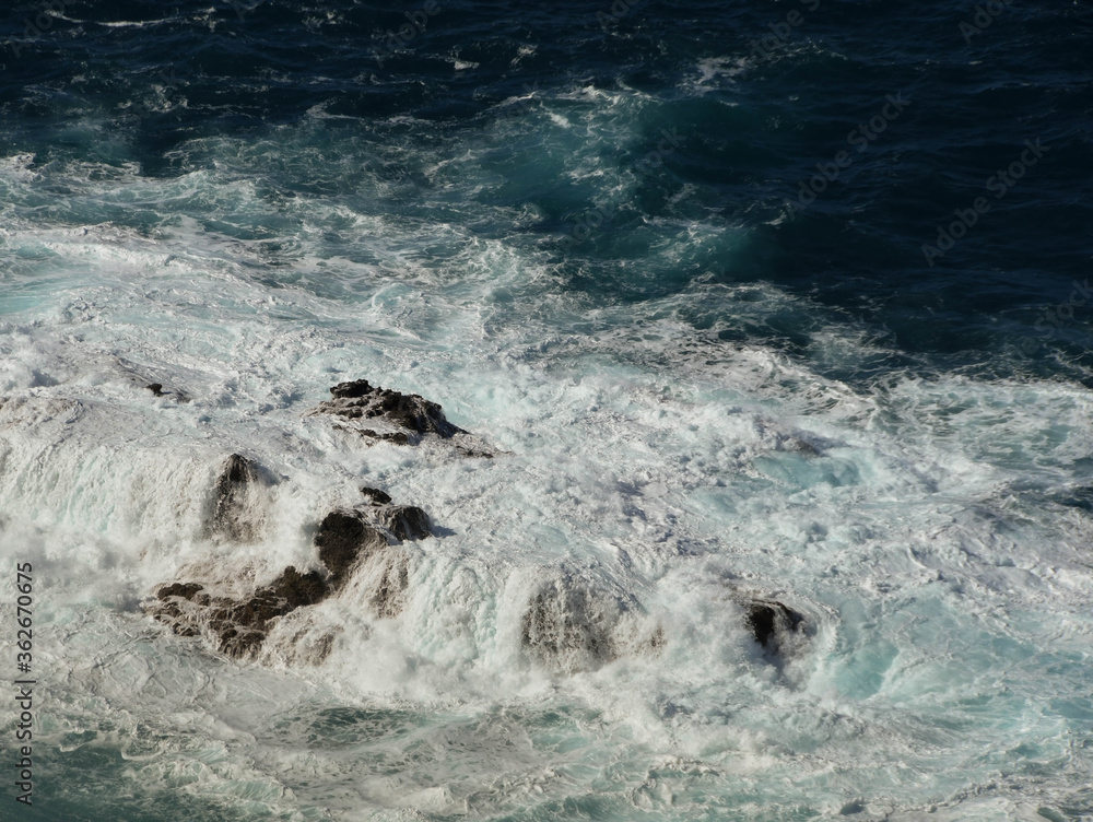 Waves and white spray crashing over rocks in the sea