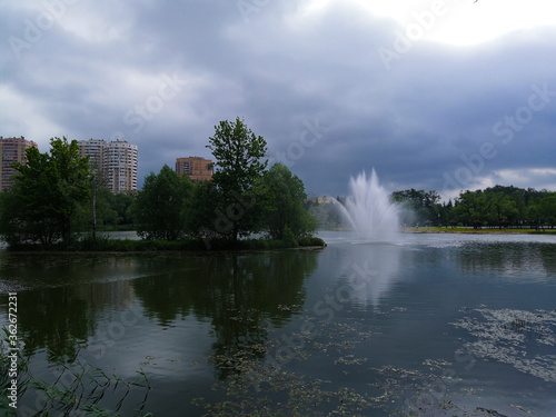 Fountain, trees in the city Park. Gloomy and rainy weather in the city. © t.karnash