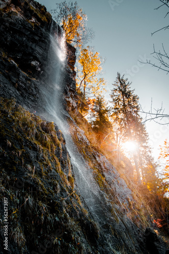 Wonderful and beautiful waterfall in the german mountains with golden autumn tones on a bright sunny day. Wild mountain river with water splash. Harz Mountains  Harz National Park in Germany.