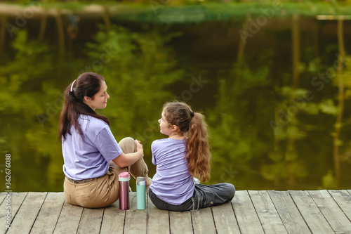 Happy family, mother and daughter resting in the park near the lake.