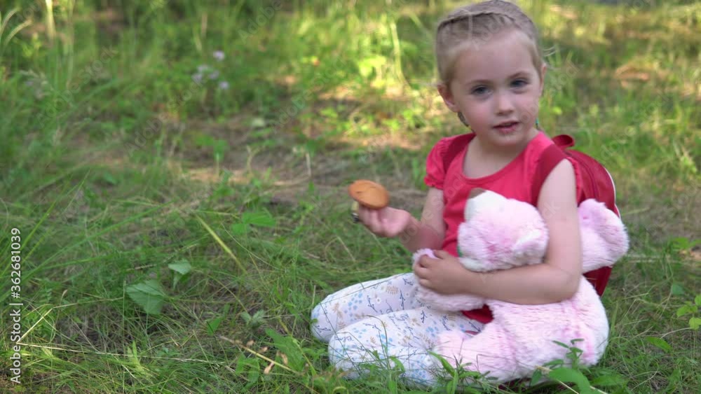 Little girl plucks a mushroom. Girl with a pink teddy bear. Little girl plucks a mushroom. Girl with a pink teddy bear.