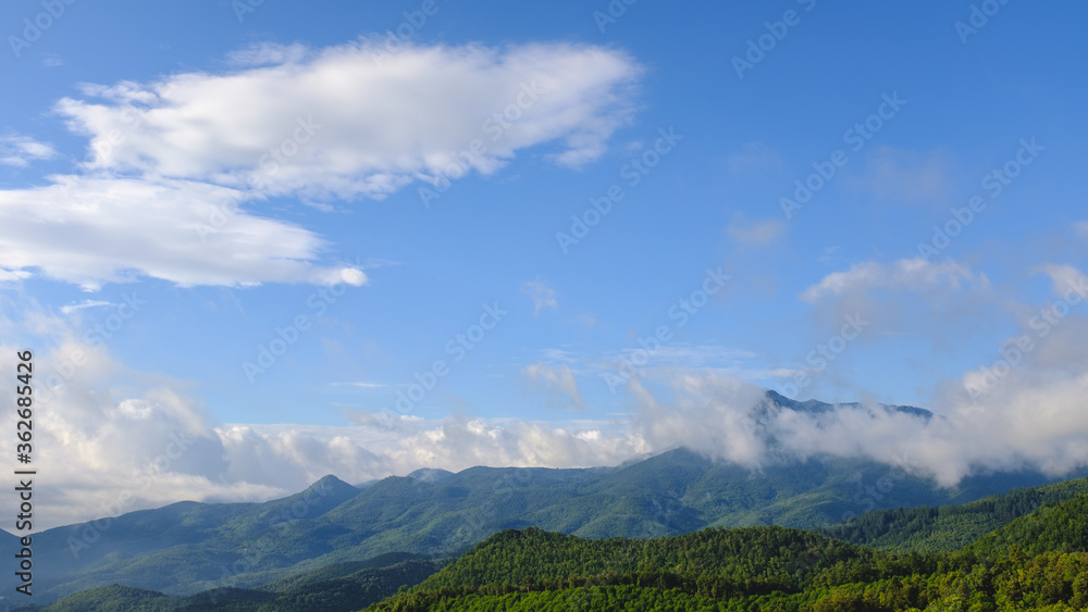Fototapeta premium Niebieski słoneczny krajobraz z niektórymi chmurami górskimi obejmującymi szczyt w Montseny w Katalonii