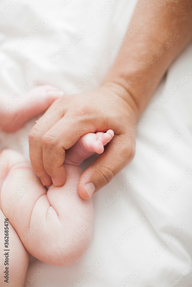 Male hand holding newborn baby's feet. Father with his baby. Family, birth concept. Health, care, love, relationship concept. Close up (Soft focus and blurry) Male hand holding newborn baby's feet. Father with his baby. Family, birth concept. Health, care, love, relationship concept. Close up (Soft focus and blurry)