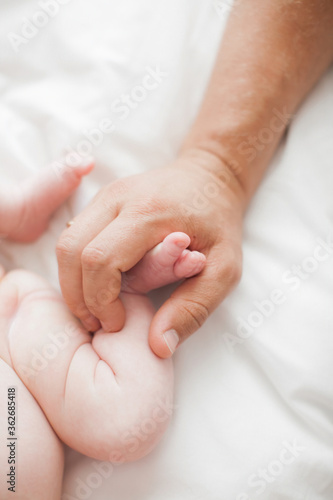 Male hand holding newborn baby's feet. Father with his baby. Family, birth concept. Health, care, love, relationship concept. Close up (Soft focus and blurry)