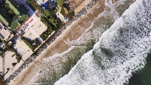 Drone shot of the Pacific ocean sand beach and houses along the coast in California on a sunny day