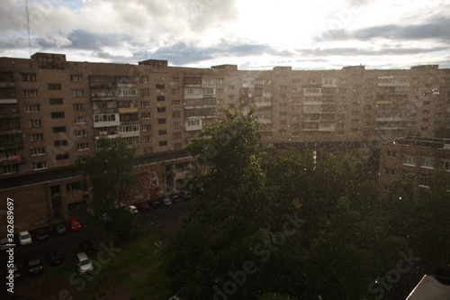 raindrops and view of apartment houses on background in warm rain in summer.
