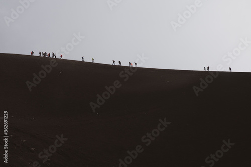 
ETNA NATIONAL PARK, SICILY, ITALY row of tourists walking on the edge of a crater an altitude of 2900 m., at the border with the area of high criticality of the volcano. photo