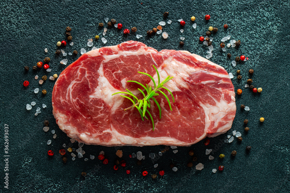 Raw fresh meat Ribeye Steak and seasoning on dark background. Top view. Flat lay