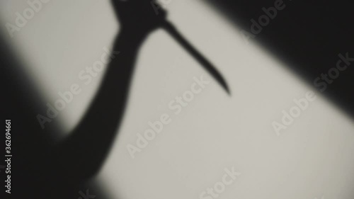 Hand of Killer Stabbing Victim with a Knife. Crime Scene. Dark Shadow on the White Background
