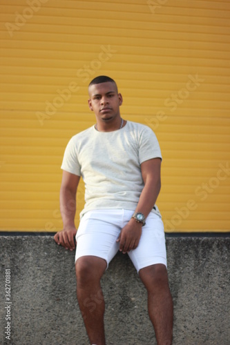 young man sitting on a yellow wall
