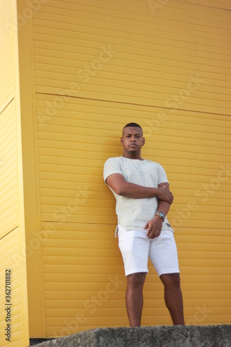 young man standing on a yellow wall