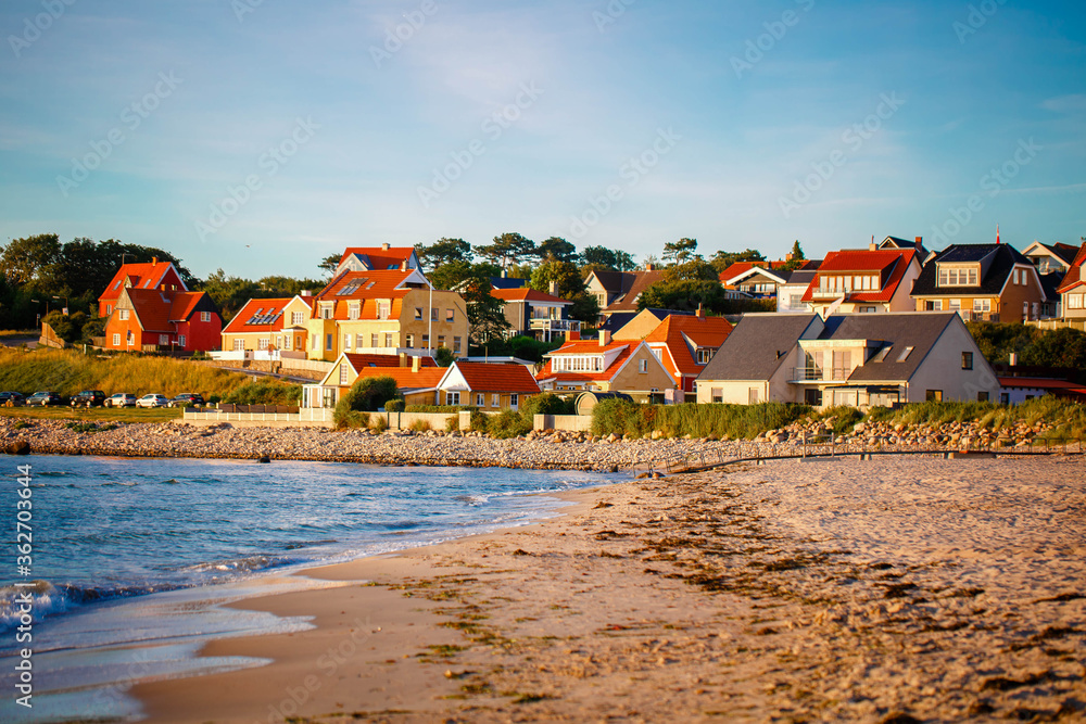 Beautiful Houses in typical yellow color on the beach with sea view during colorful sunset. Denmark, North Sea