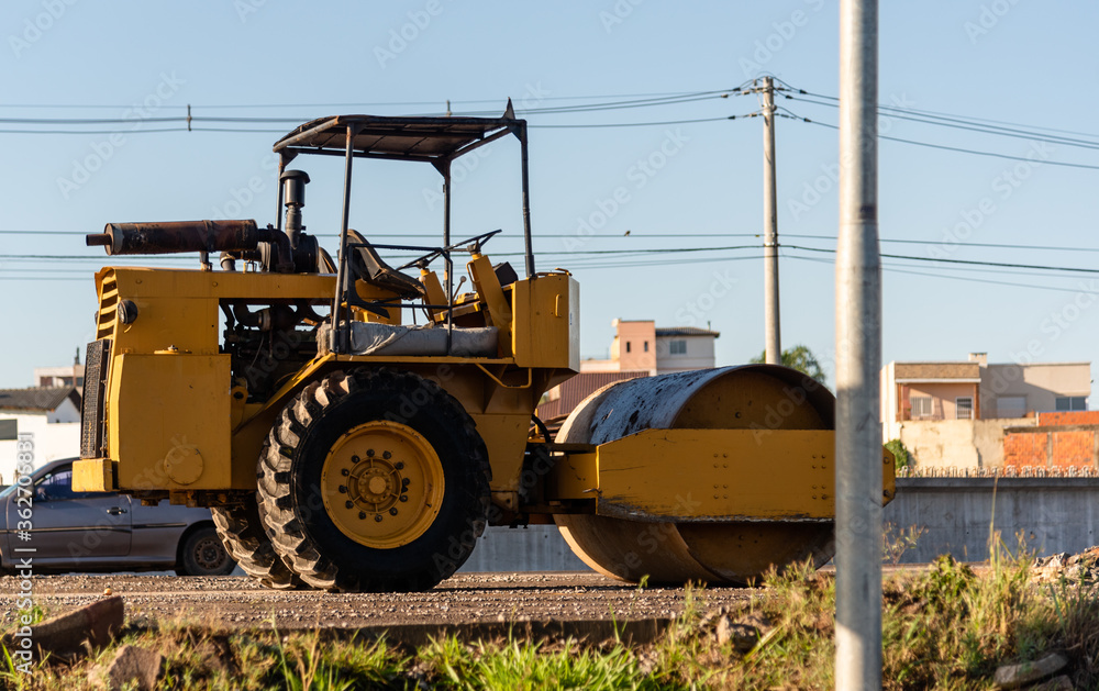 Yellow Smooth or Single-drum roller parked on a highway Yellow Smooth or Single-drum roller parked on a highway