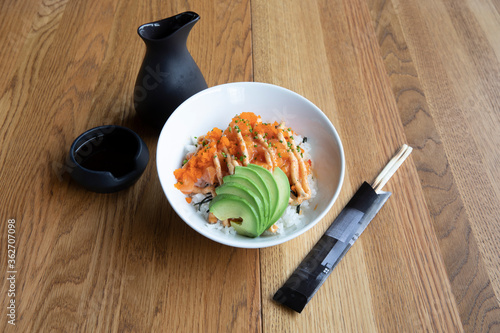 Obraz na plátně A bowl of salmon, avocado, and rice on a table. Japanese food.