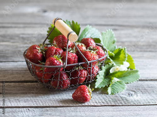 Strawberries in a basket on a wooden background in summer