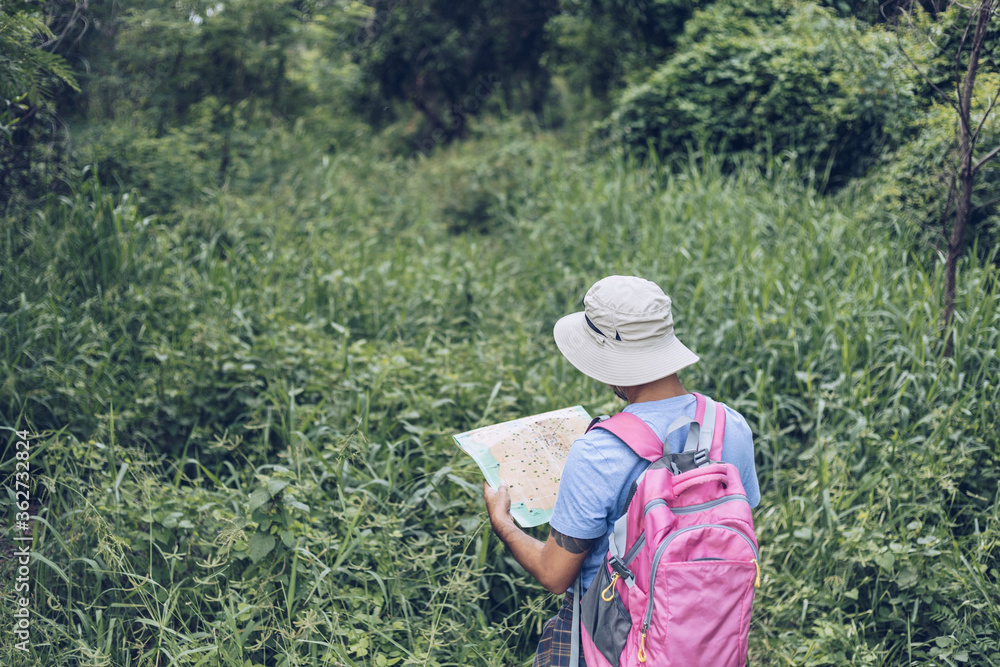 Young asian man backpacker looking at map in nature ,Lifestyle hiking concept
