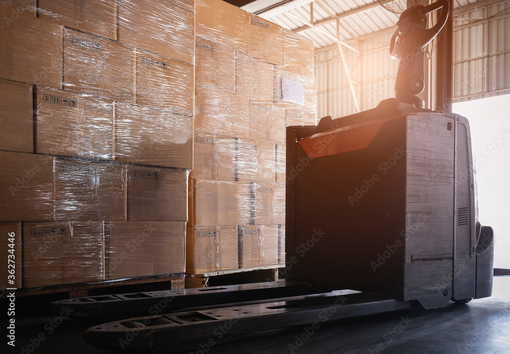 Electric forklift pallet jack with stack of shipment boxes at the warehouse. Electric forklift pallet jack with stack of shipment boxes at the warehouse.