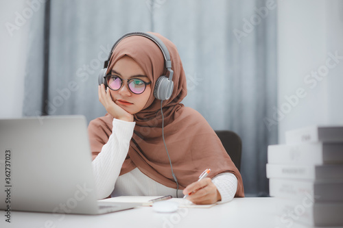 Beautiful muslim student girl using a laptop computer learning online at home. Distance learning online education. photo