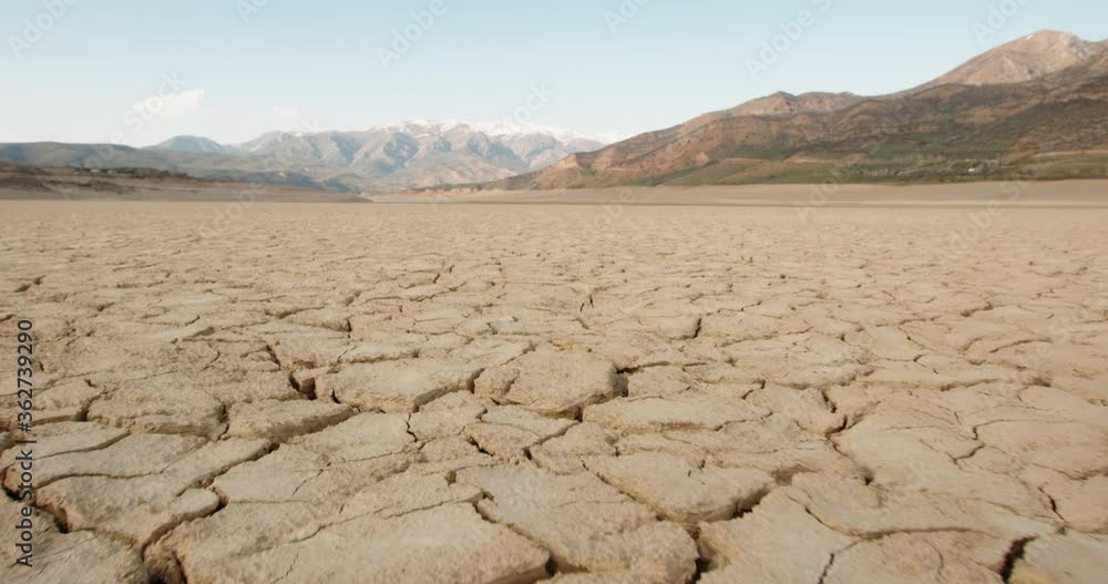Dynamic shot of cracked soil ground of dried lake or river in mountains ...