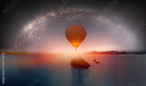 The milky way galaxy over the sea and silhouette of rock in the night sky - Hot air balloon flying over night sea