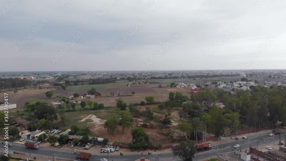 Most Beautiful aerial view of the land in green fields nearby residential area on a cloudy day Most Beautiful aerial view of the land in green fields nearby residential area on a cloudy day
