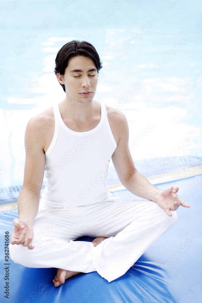 Fototapeta premium Man meditating by the pool side