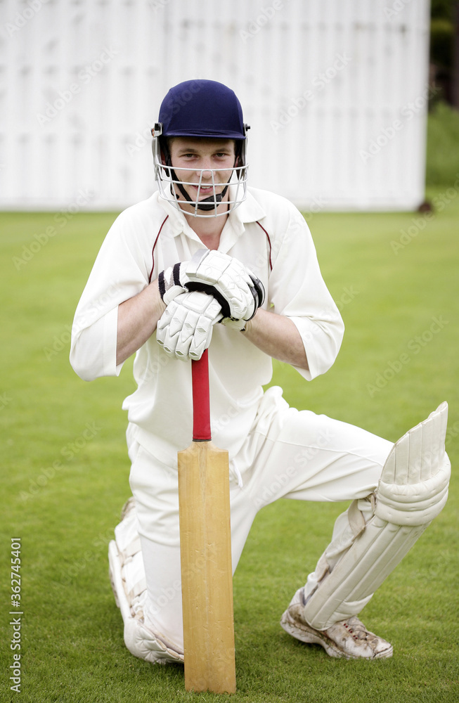 Obraz premium Man kneeling down while holding a cricket bat