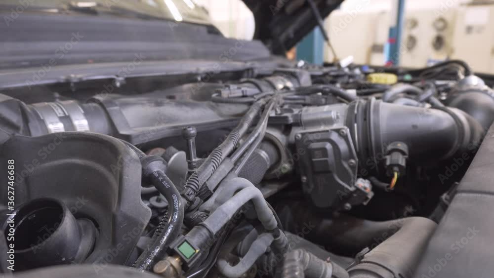 Car mechanic looking for a smoke source from the engine under the bonnet in the car workshop. Car mechanic looking for a smoke source from the engine under the bonnet in the car workshop.