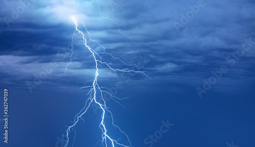 Lightning strikes between blue stormy strange clouds.