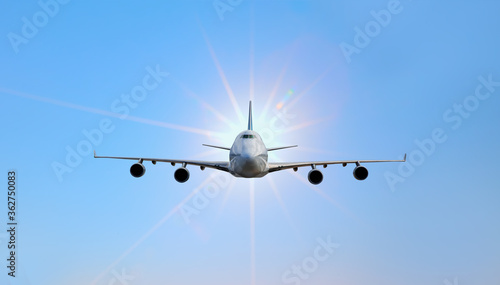 White passenger airplane in the blue sky with sunrays - Travel by air transport 