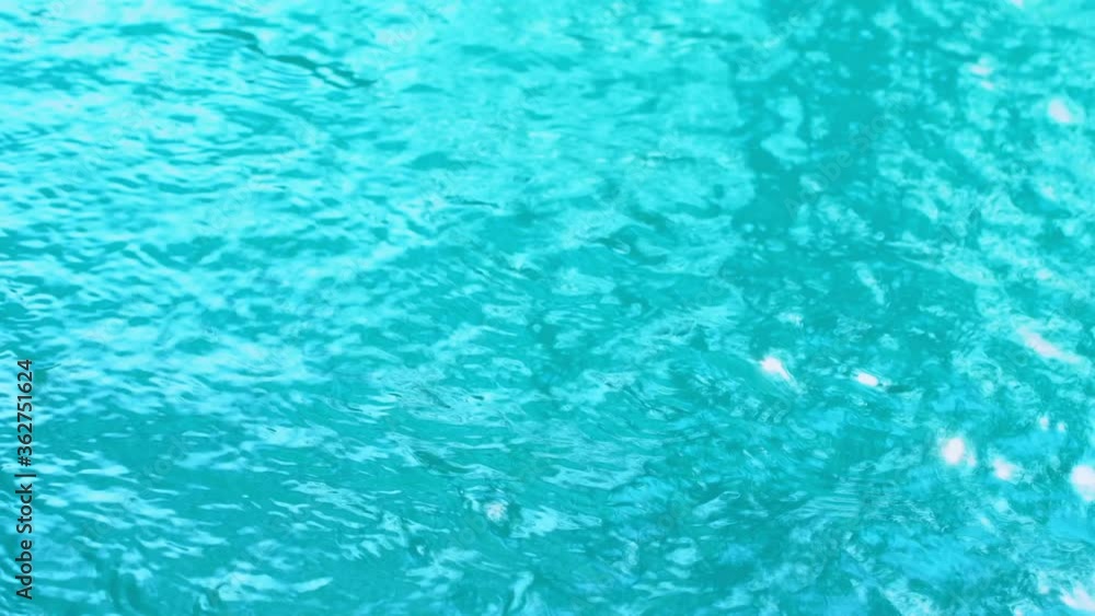 Beautiful sparkling shiny texture of blurry blue water with sun reflected on surface of water Beautiful sparkling shiny texture of blurry blue water with sun reflected on surface of water