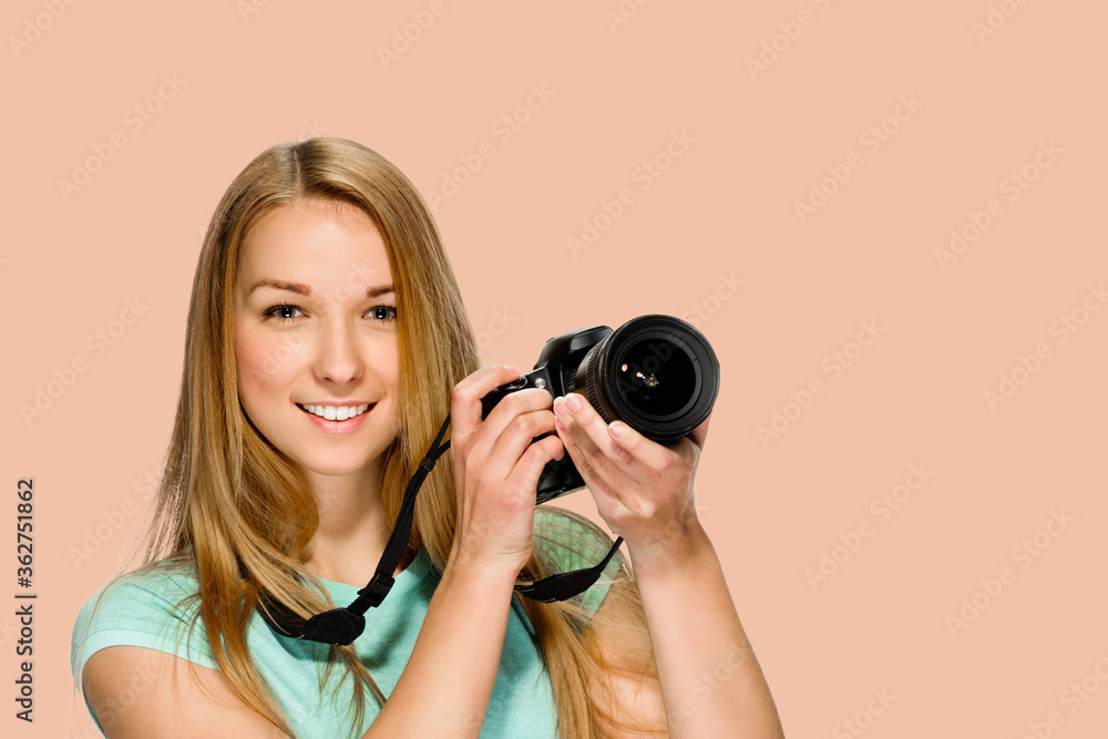 Happy young journalist with professional camera posing on salmon red background Happy young journalist with professional camera posing on salmon red background