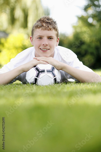 Boy lying forward with his chin resting on a soccer ball