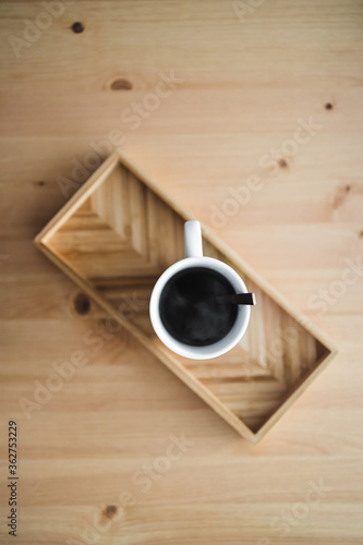 mug of black coffee on bamboo tray on wooden table