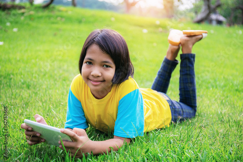 Asian girl using tablet on lawn. photo