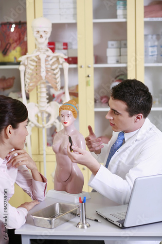 Doctor pointing at anatomical model, patient watching