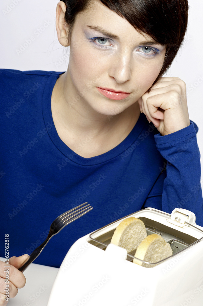 Woman holding a fork waiting for her toast Woman holding a fork waiting for her toast