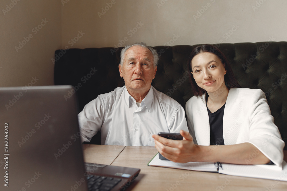 Senior with a young assistant. Businessman working in the cafe. Man in a white shirt. Young woman with her boss. Senior with a young assistant. Businessman working in the cafe. Man in a white shirt. Young woman with her boss.